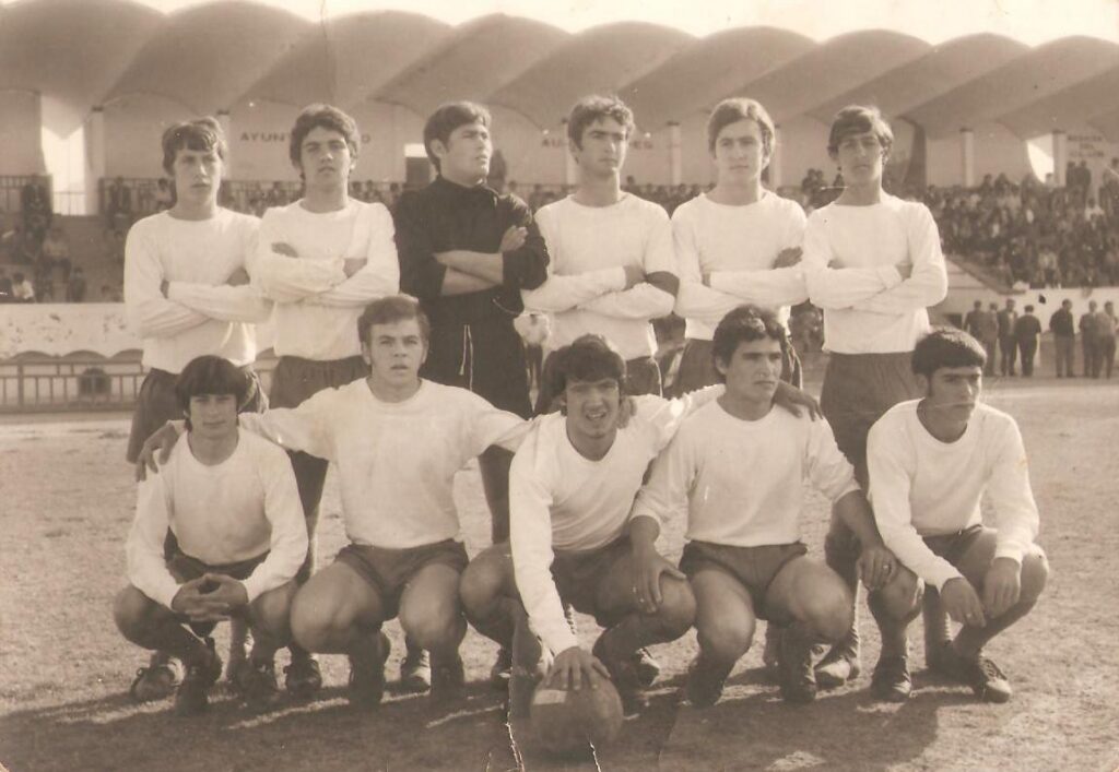Equipo de fútbol juvenil posando en el campo con balón