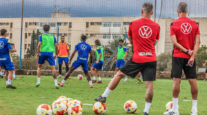 Jugadores de la U.D. Melilla entrenando en el campo con balones de fútbol.