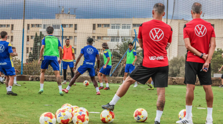Jugadores de la U.D. Melilla entrenando en el campo con balones de fútbol.