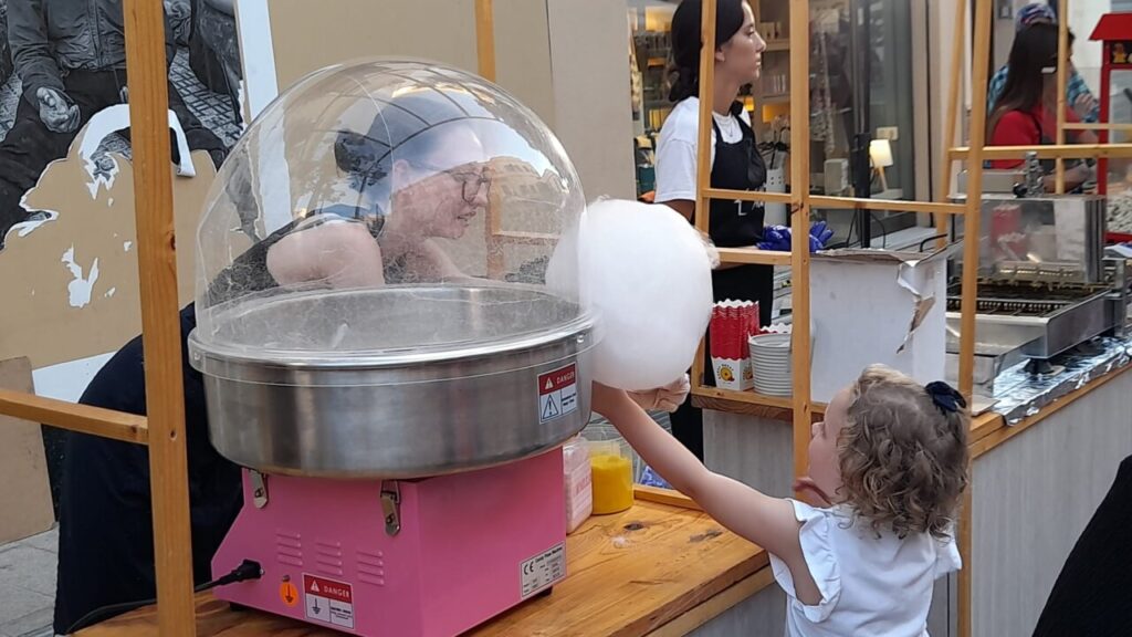 Niña recibiendo algodón de azúcar en una verbena popular en Melilla.