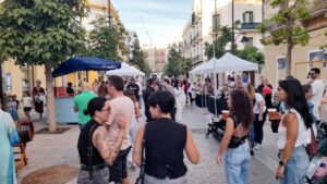 Gente disfrutando de una verbena popular en Melilla con juegos y música.