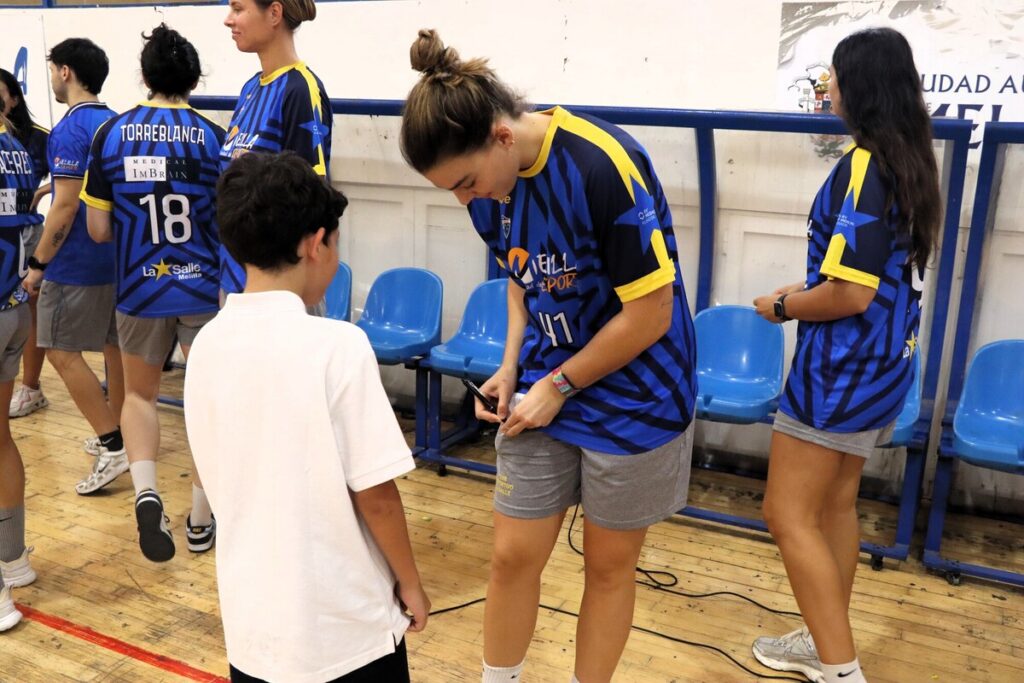 Jugadora de baloncesto interactuando con un niño en el pabellón.