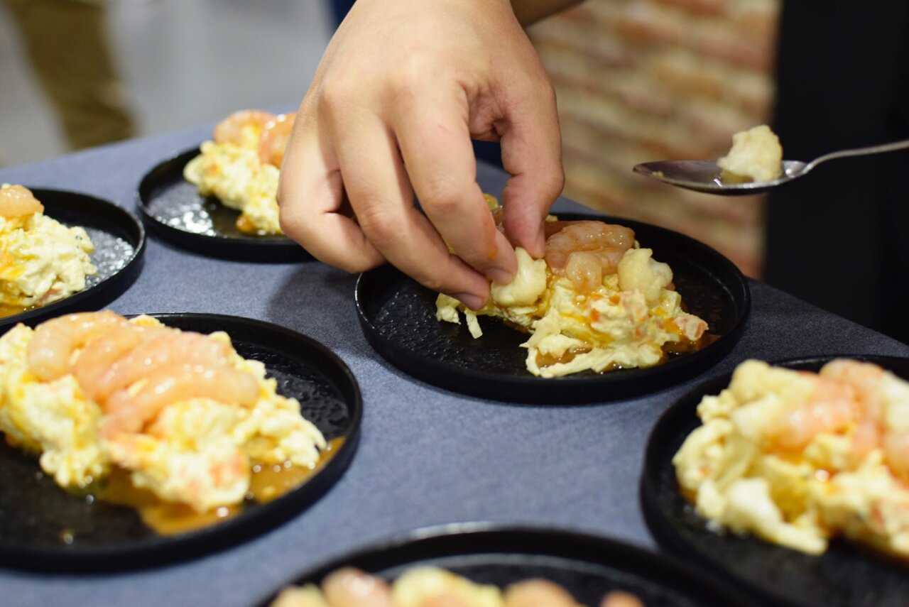 Plato de ensaladilla rusa con mariscos en un evento gastronómico.