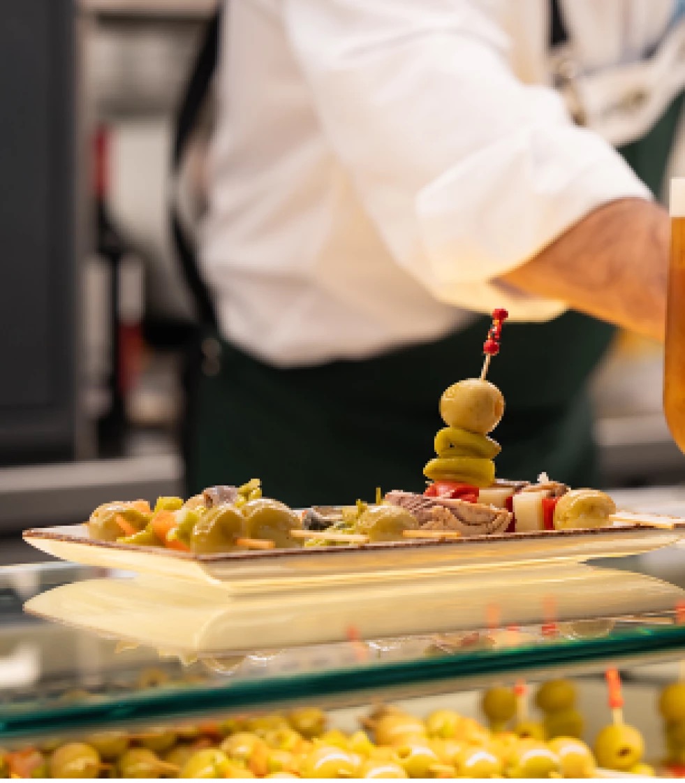 Plato de tapas con aceitunas y otros ingredientes en Bernabéu Market
