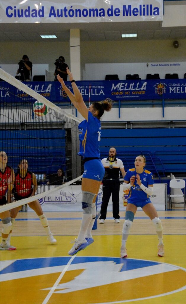 Jugadora del Club Voleibol Melilla saltando para bloquear un remate en el partido.