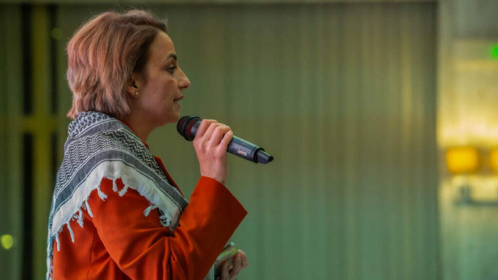 Mujer hablando con micrófono en un evento de CPM.