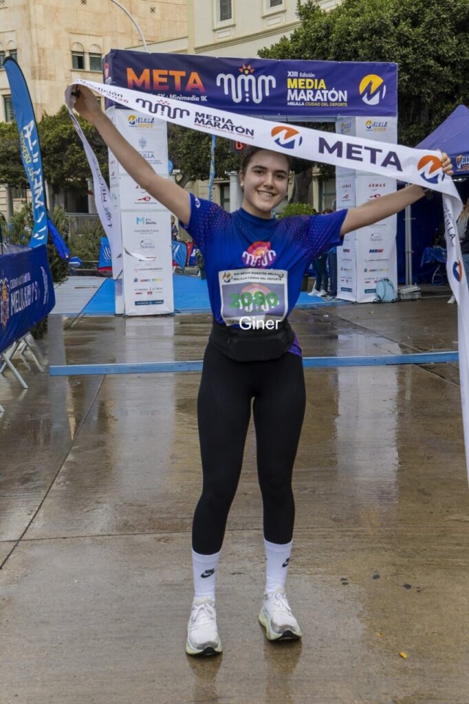 Corredora sonriente cruzando la meta en la Media Maratón de Melilla