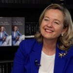 Nadia Calviño sonriente junto a su libro sobre su experiencia en el Gobierno.