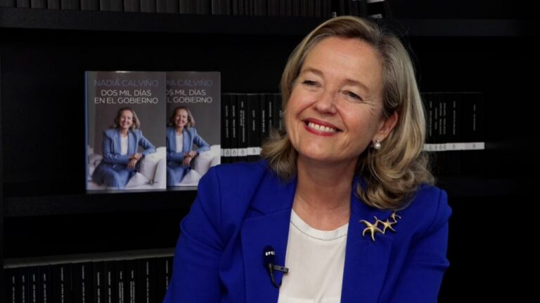 Nadia Calviño sonriente junto a su libro sobre su experiencia en el Gobierno.