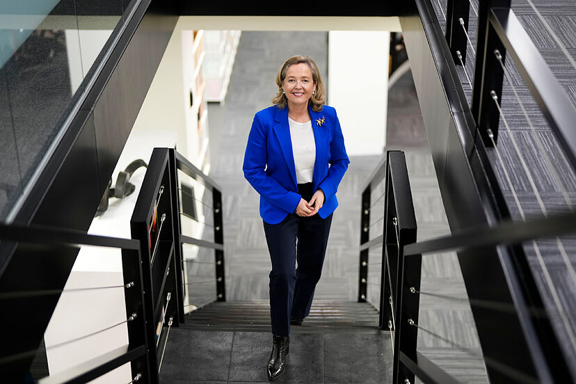 Nadia Calviño sonriendo mientras sube escaleras en un entorno moderno