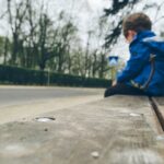 Niño sentado en un banco, reflexionando sobre la pobreza infantil.