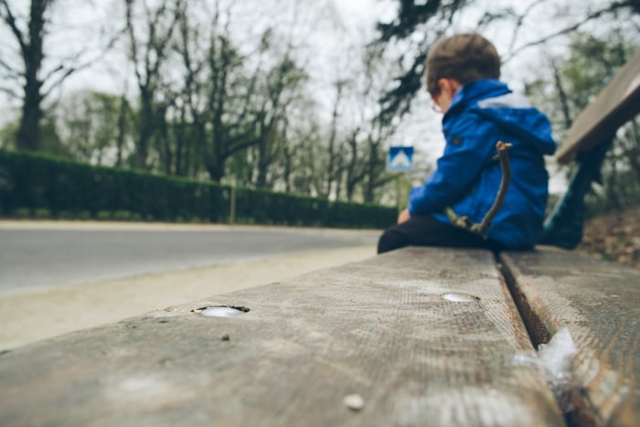 Niño sentado en un banco, reflexionando sobre la pobreza infantil.