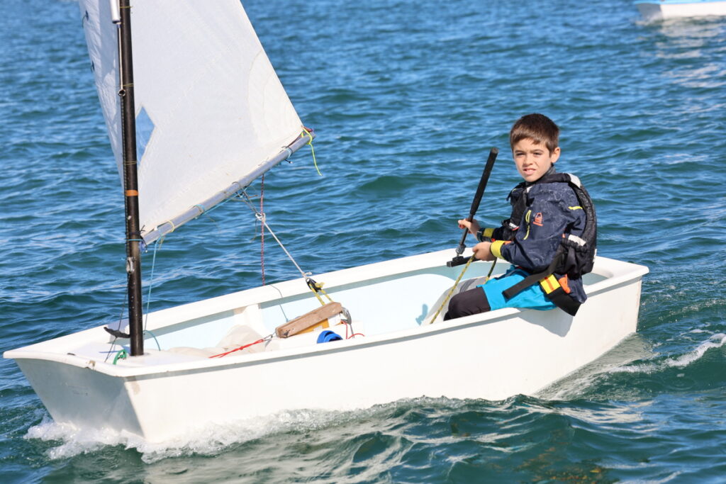 Niño navegando en un barco pequeño durante una regata de vela.