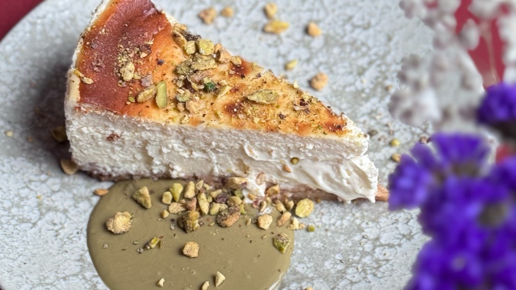 Porción de cheesecake con pistachos y salsa en un plato