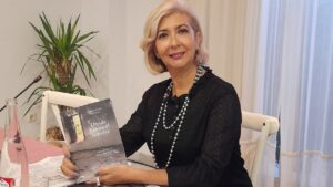 Claudia Luna sosteniendo su libro de poemas en un evento