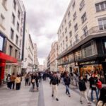 Avenida concurrida en Madrid con tiendas y gente caminando.