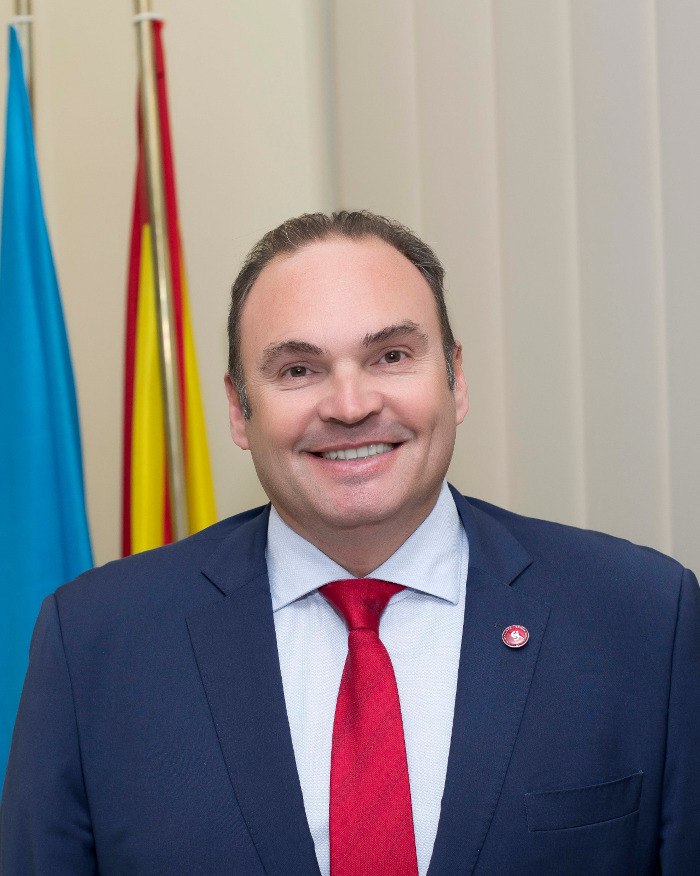 Retrato de un hombre sonriendo en un entorno académico