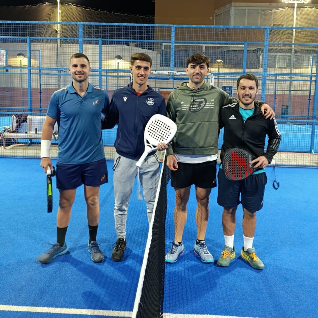 Cuatro jugadores de pádel posando en una cancha azul