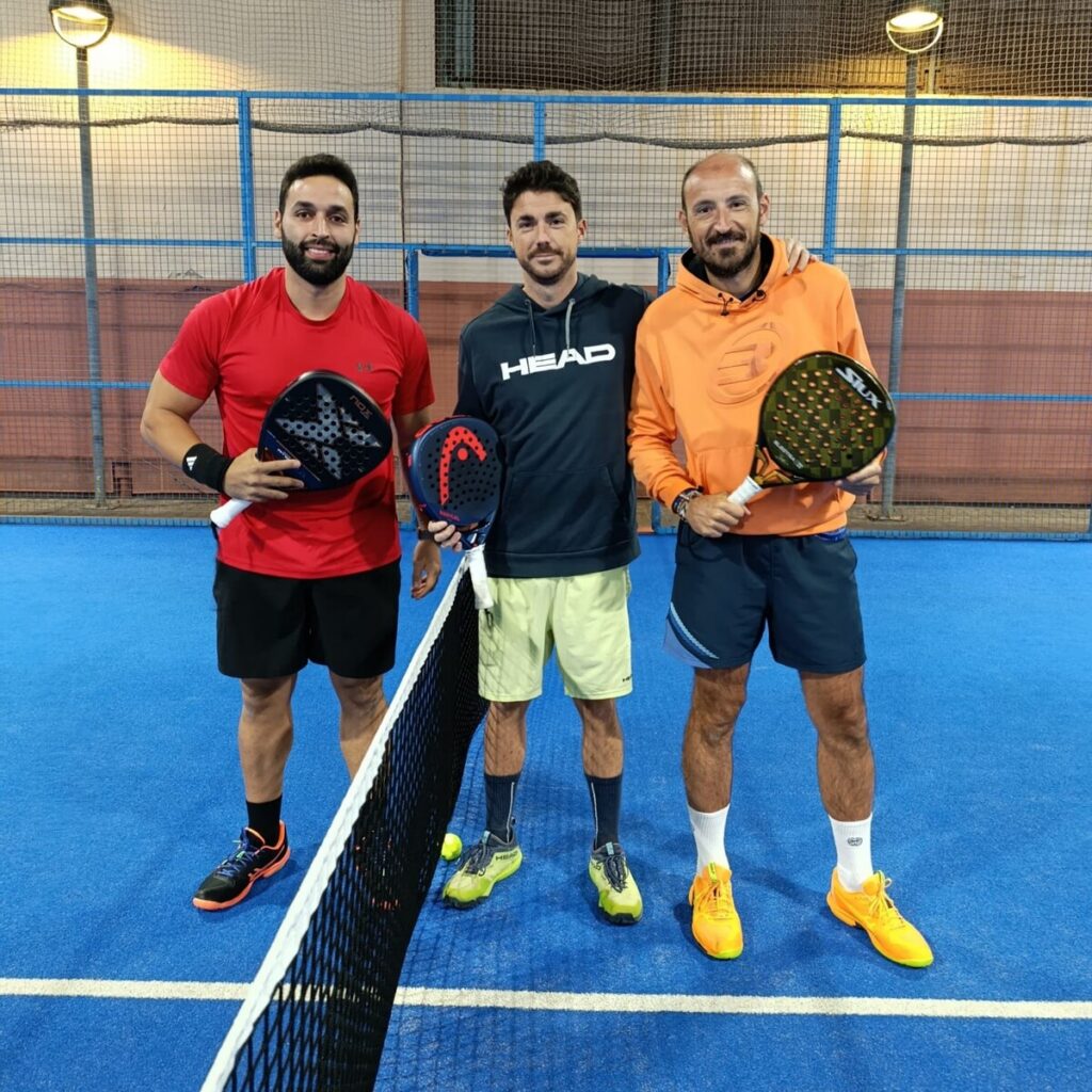 Tres jugadores de pádel posando en una cancha con raquetas