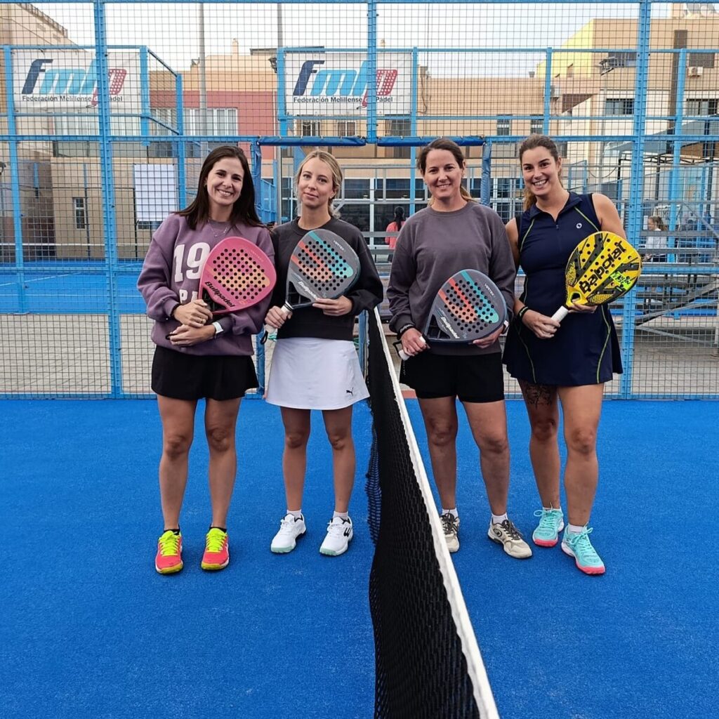 Cuatro mujeres posando con palas de pádel en una cancha