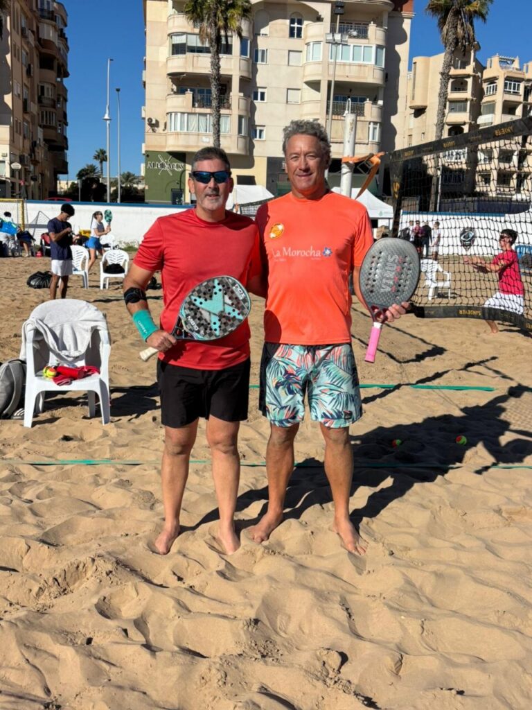 Dos jugadores de tenis playa posando en la arena con palas