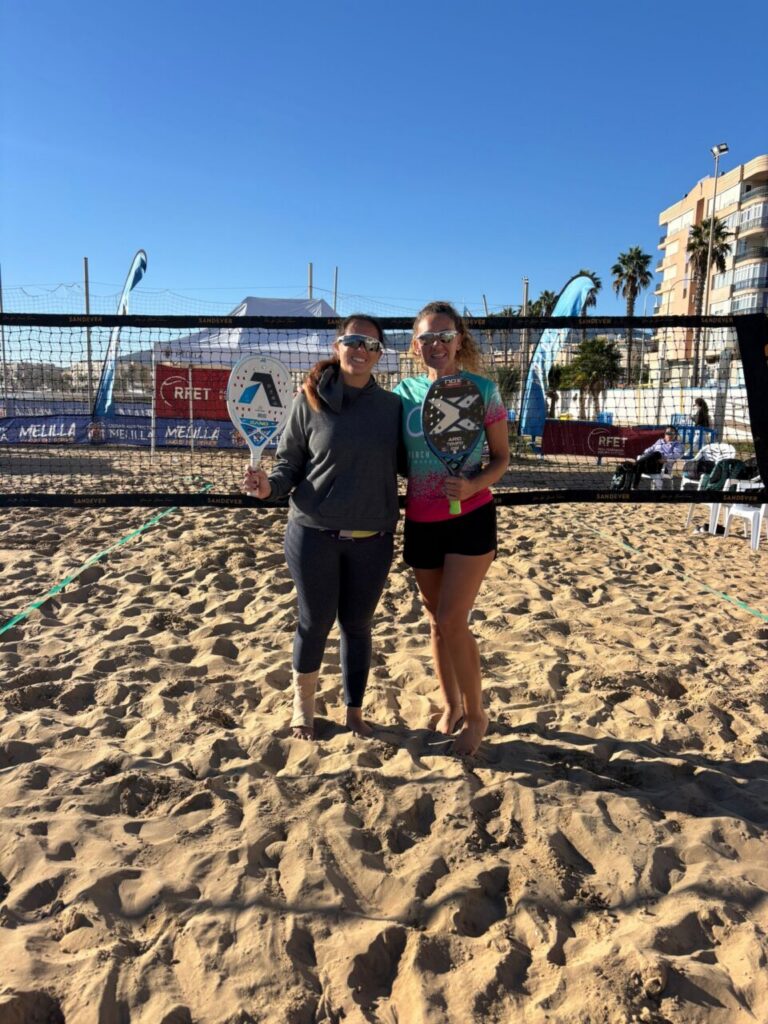 María Martínez y otra jugadora sosteniendo trofeos en la playa