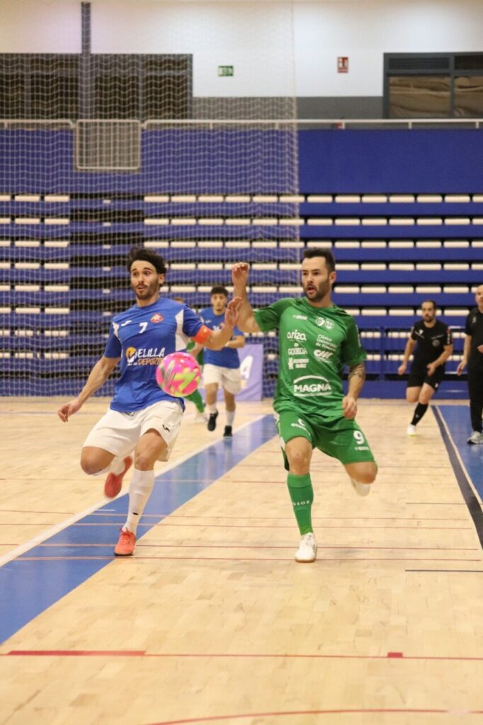 Dos jugadores de futbol sala corriendo tras un balón en la cancha.