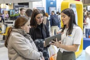 Tres personas interactuando en un evento educativo con una tablet.
