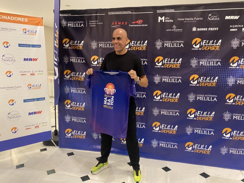 Reyes Estévez sosteniendo una camiseta de la Media Maratón de Melilla