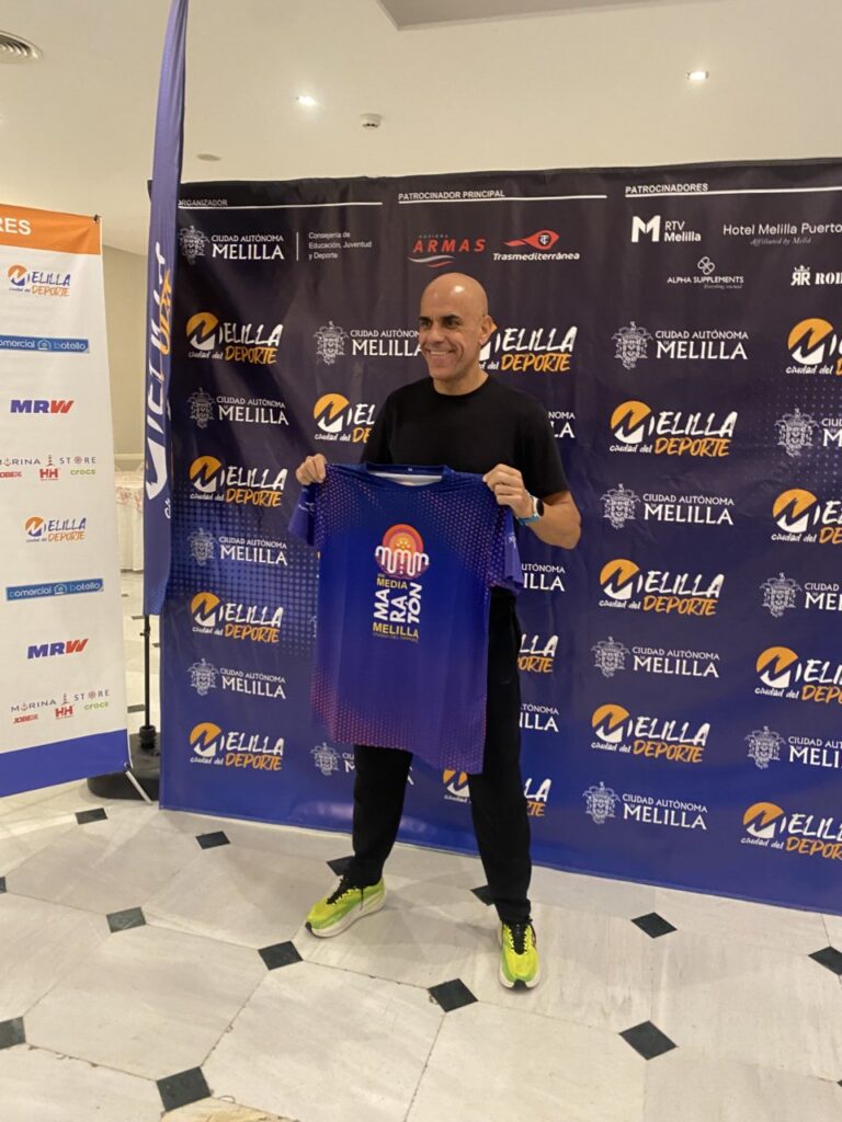 Reyes Estévez sosteniendo camiseta de la Media Maratón Ciudad de Melilla