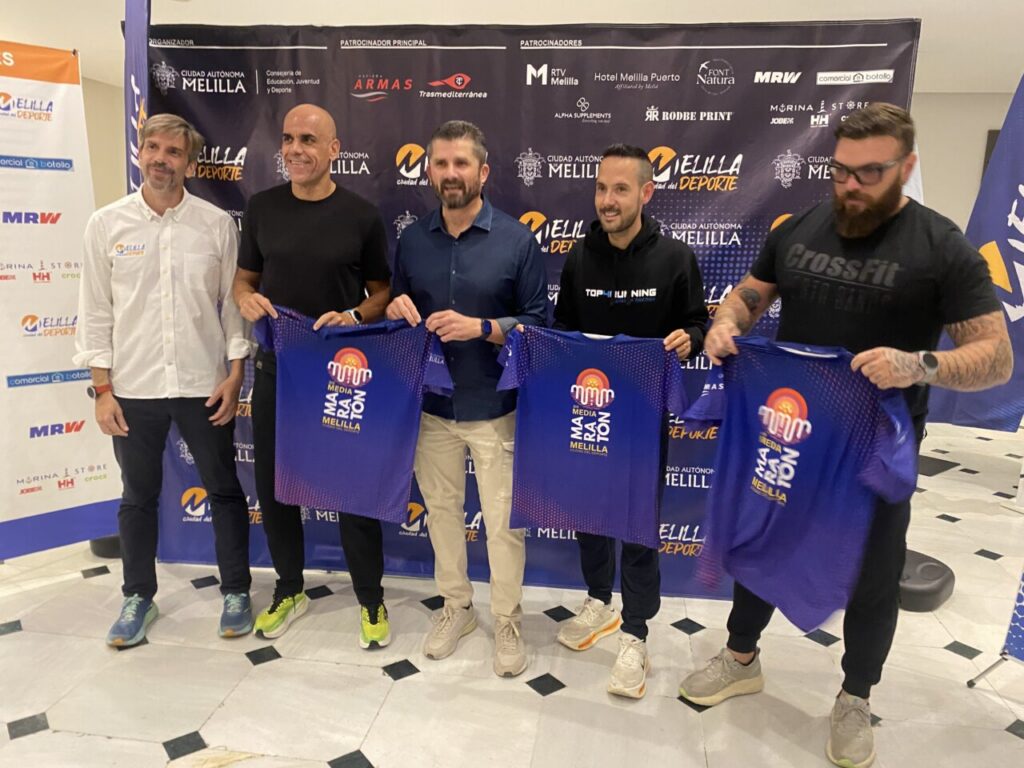 Reyes Estévez y otros atletas sosteniendo camisetas en evento de media maratón.