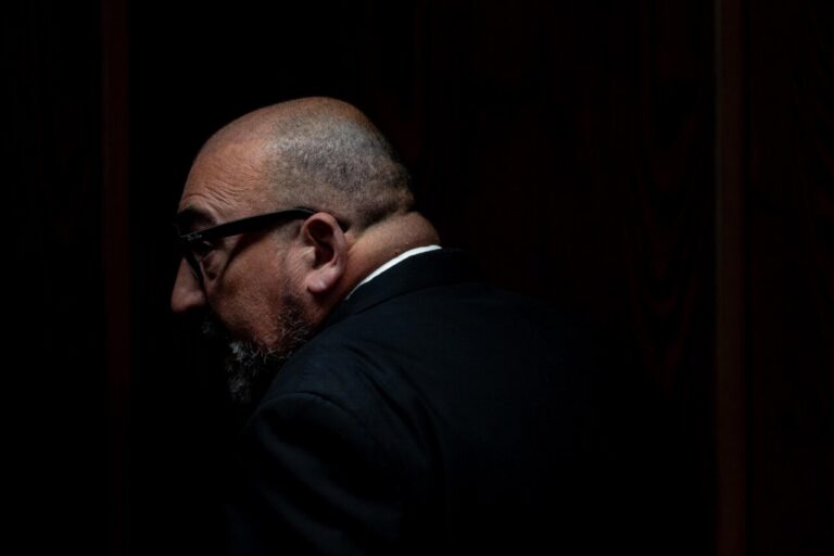 Koldo García en un entorno oscuro, con un traje y gafas.