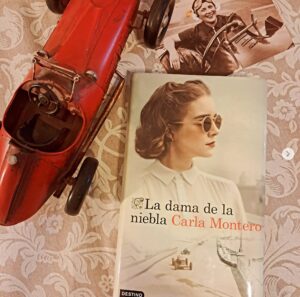 Portada del libro La dama de la niebla junto a un coche de juguete