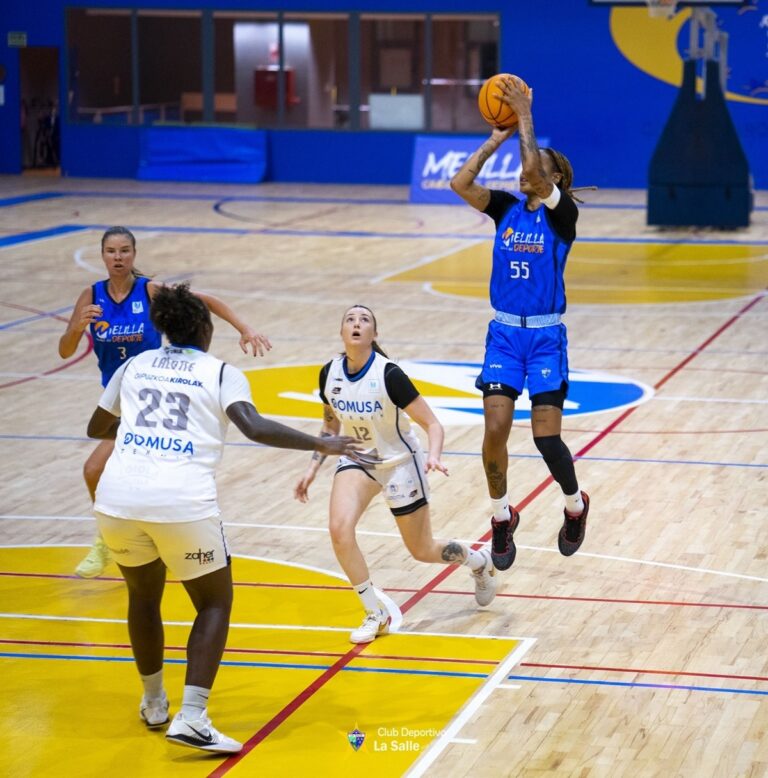 Jugadora lanzando el balón en un partido de baloncesto femenino