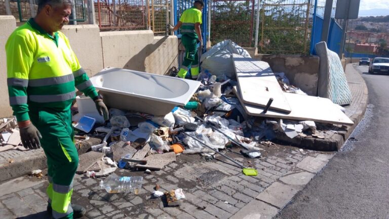 Operarios limpiando residuos en la calle Vía Láctea con maquinaria pesada.