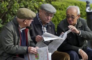 Tres hombres mayores con gafas leyendo periódicos en un parque