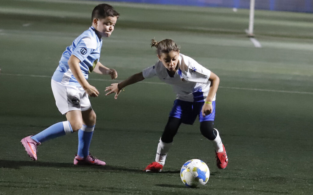 Niños jugando al fútbol en el campo durante la Copa Federación Benjamín