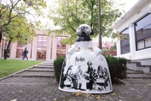 Escultura de Menina en braille en Madrid con fondo de árboles.