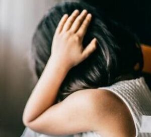 Niña con migraña cubriendo su cabeza con las manos