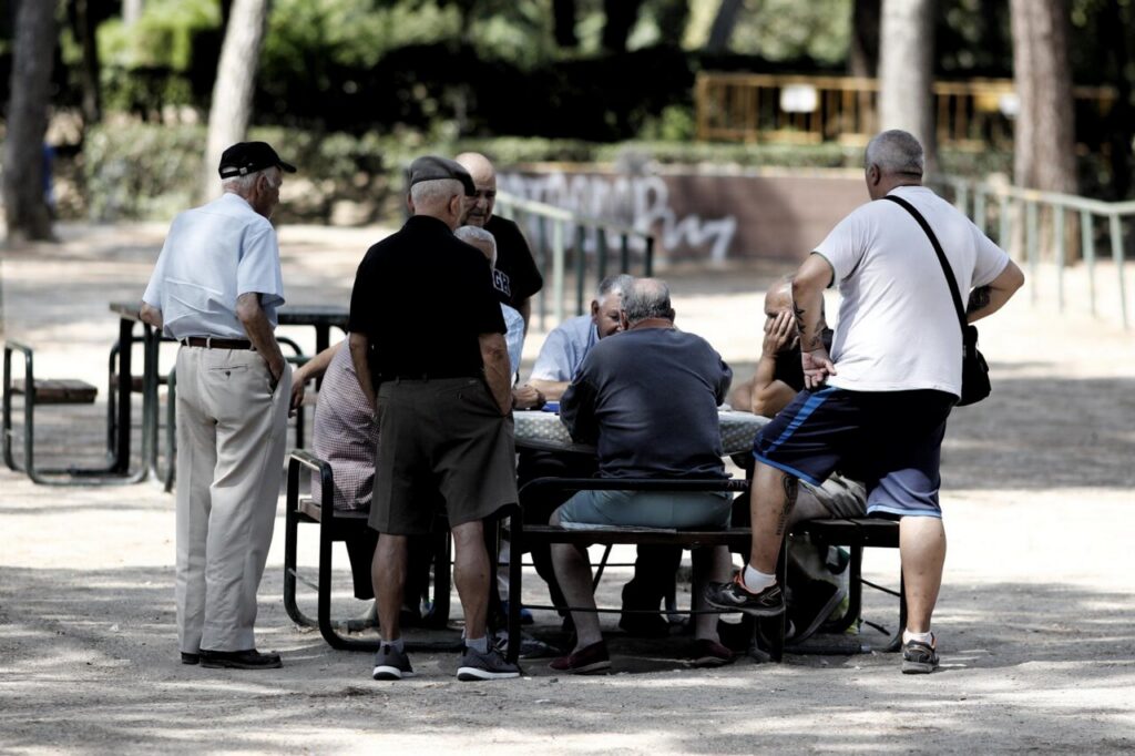 Grupo de pensionistas conversando en un parque al aire libre.
