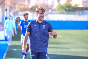 Pepe Arredondo, entrenador de la U.D. Melilla B, sonríe en el campo.