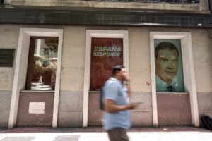 Persona caminando frente a una oficina del PSOE con carteles visibles
