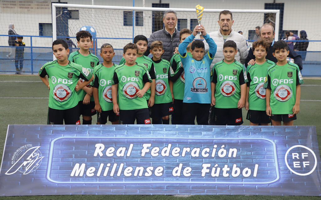 Equipo de fútbol juvenil con trofeo en el campo de fútbol