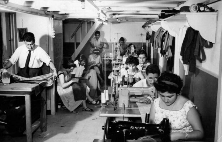 Taller de sastrería con varias personas trabajando en máquinas de coser.