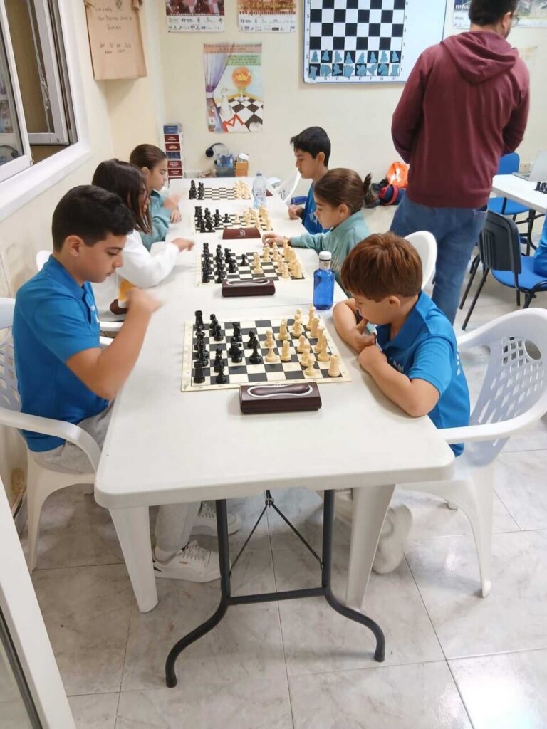 Niños jugando ajedrez en una mesa durante un torneo