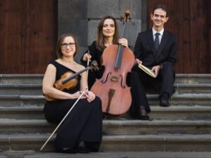 El Trío Ravel posando en escaleras con instrumentos musicales