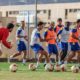 Jugadores de la U.D. Melilla entrenando en el campo con balones de fútbol.