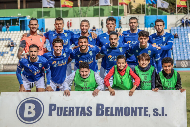 Jugadores de la U.D. Melilla posando en el estadio con aficionados