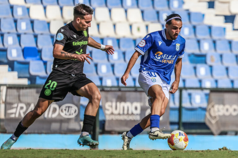 Jugadores de la U.D. Melilla y Águilas F.C. en acción durante un partido de fútbol.