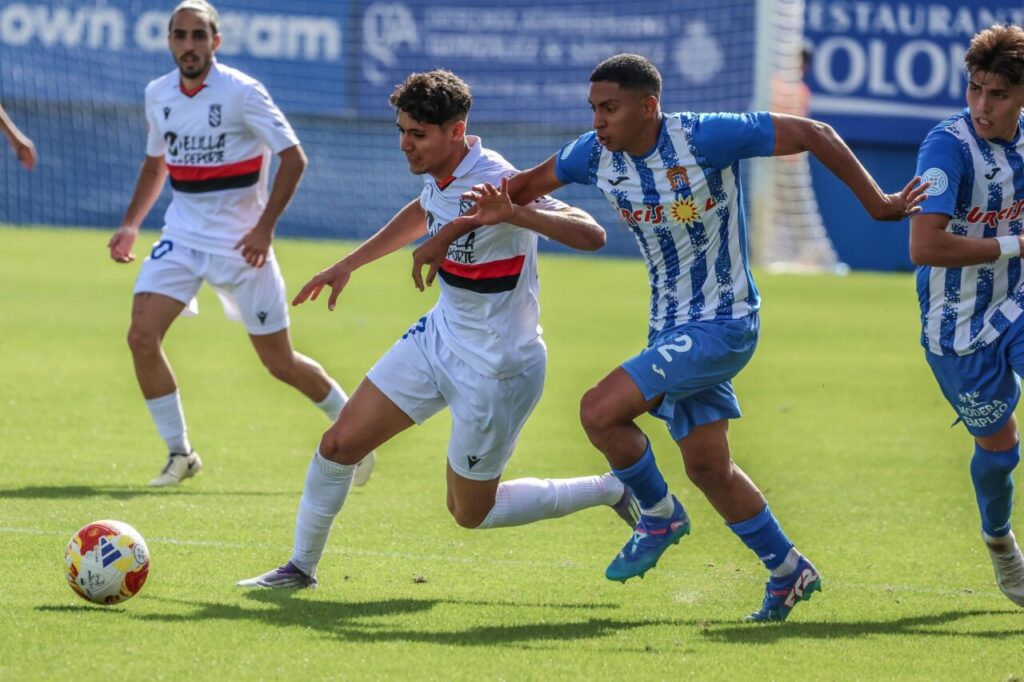 Jugadores de la U.D. Melilla y Águilas CF compiten por el balón en un partido de fútbol.